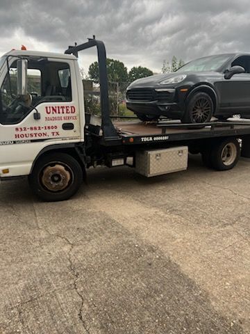 Tow truck carrying a gray SUV in a parking lot with a United towing logo on the cab