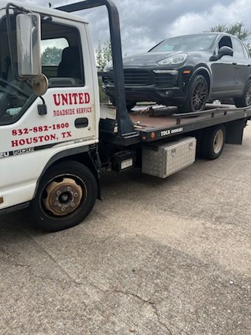 Tow truck loading a gray SUV in a parking lot, with “United Wrecker Service” on the door.