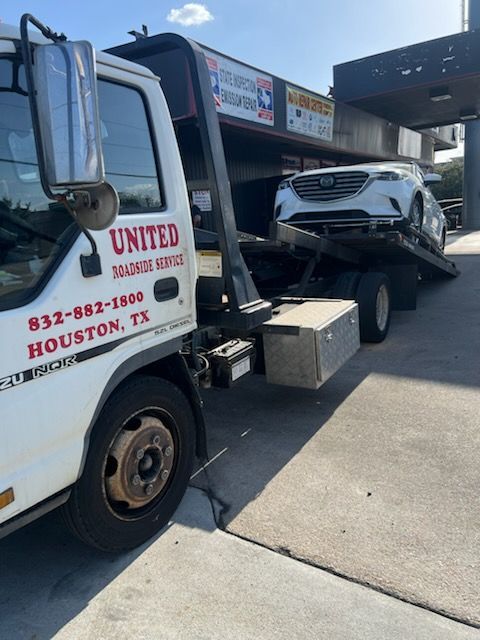 Boat being towed on a trailer behind a white SUV on a road.