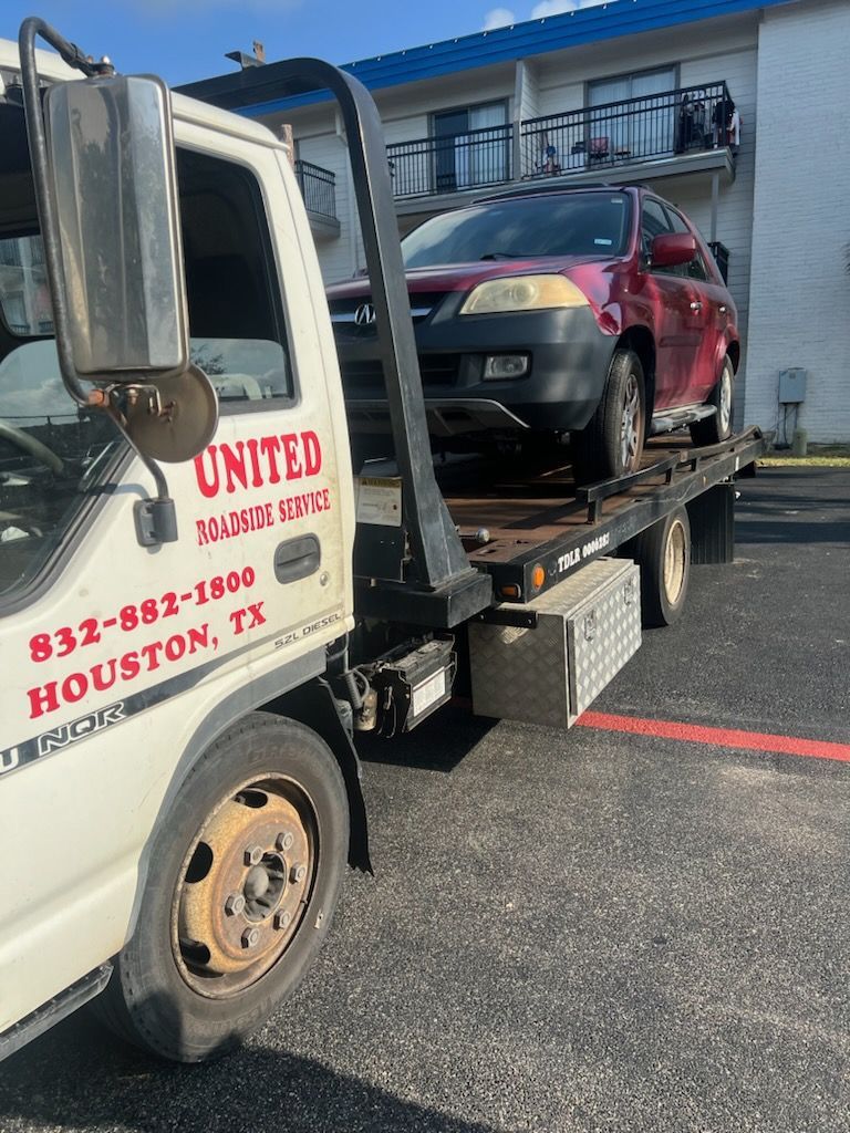 Tow truck loading a maroon minivan on a flatbed in a parking lot