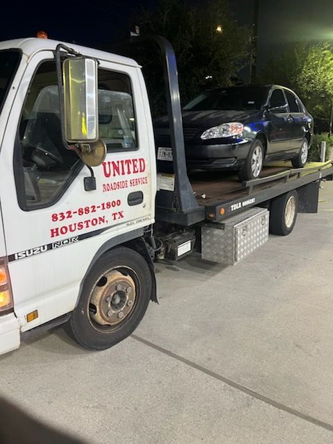 Tow truck lifting a damaged gray car on a city street