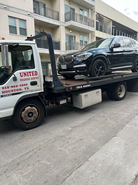 Boat being towed on a trailer behind a white SUV on a road.