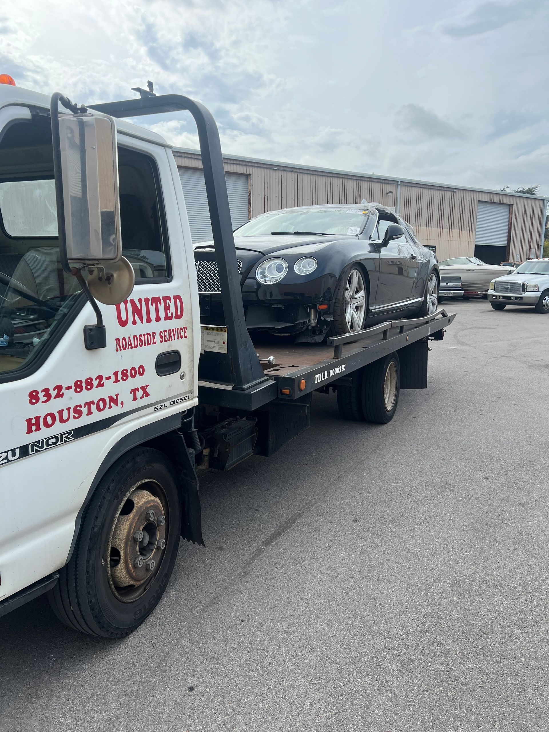 Tow truck hauling a black car in an industrial parking lot