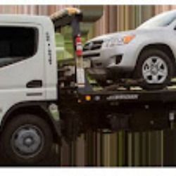 White tow truck carrying a silver SUV on a flatbed