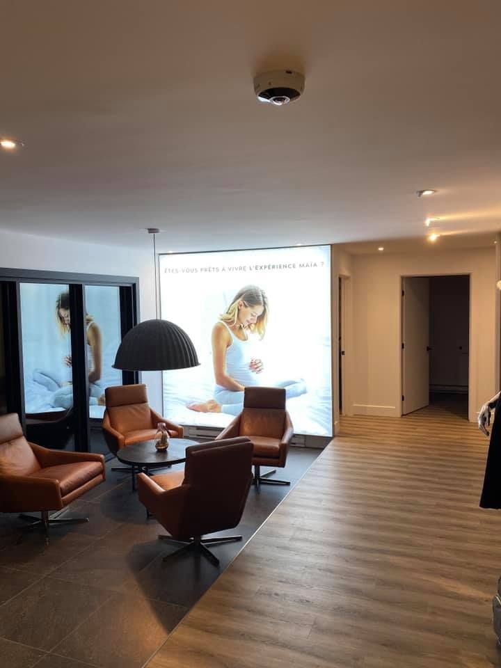 Waiting area with brown leather chairs, circular coffee table, and large backlit photo.