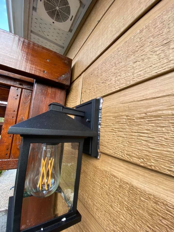 Black outdoor lamp mounted on brown siding.