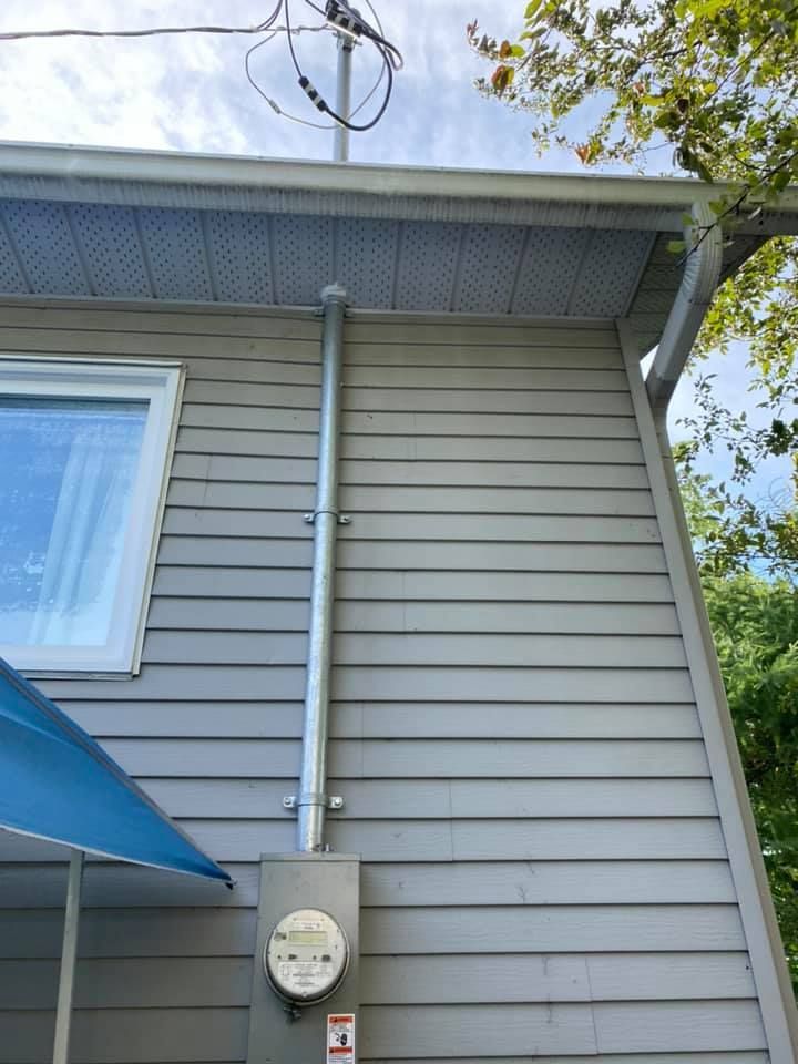 Gray house exterior with metal electrical conduit running down to a utility meter.
