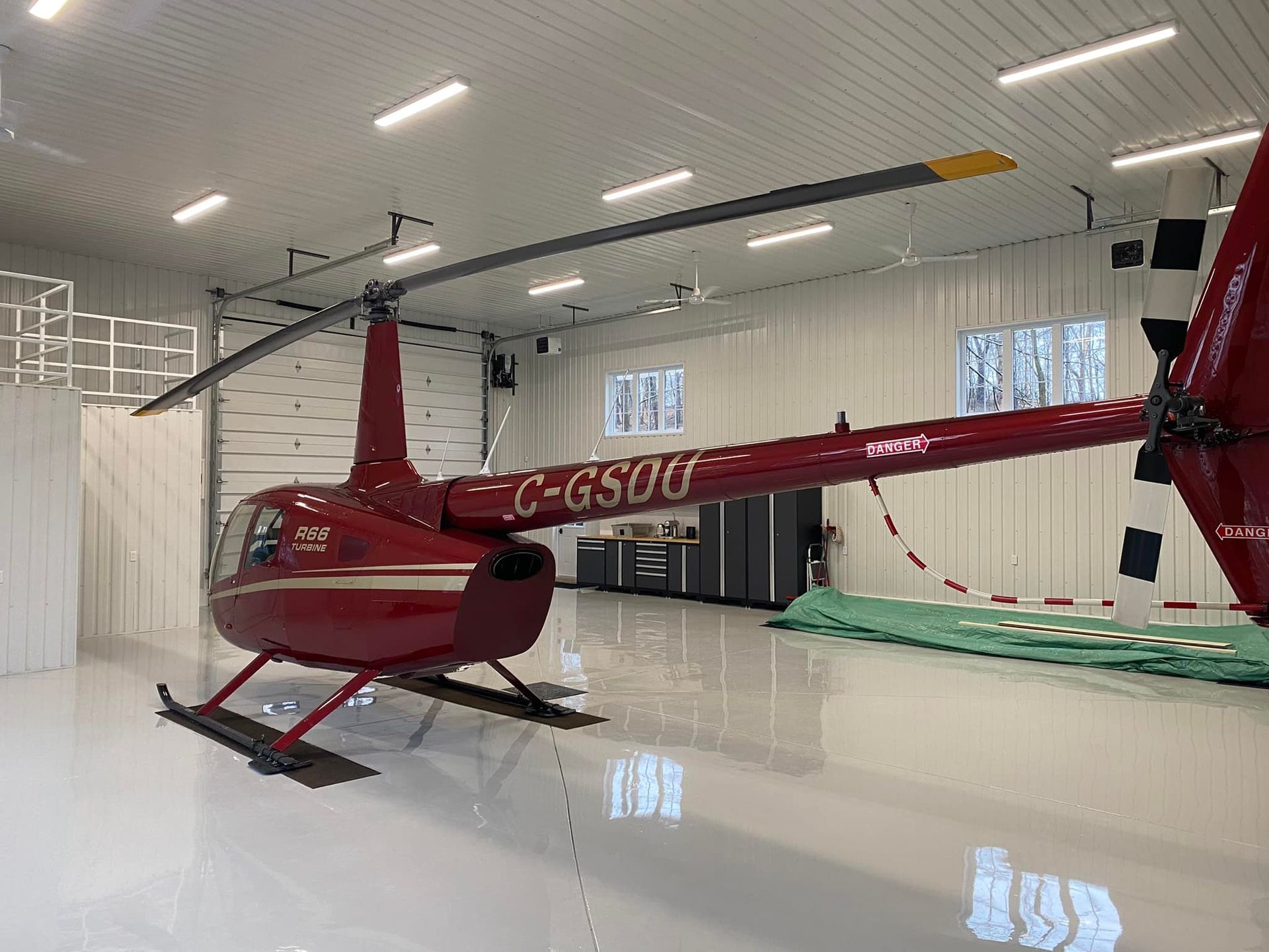 Red helicopter in a white hangar, reflective floor, labeled C-GSOC.