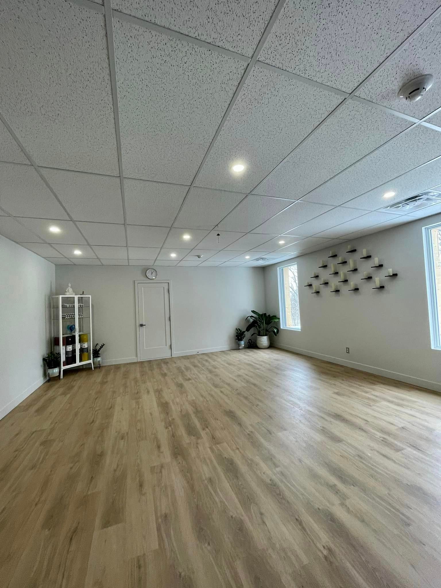 Empty, well-lit studio with light wood floor, white walls, and a textured ceiling.