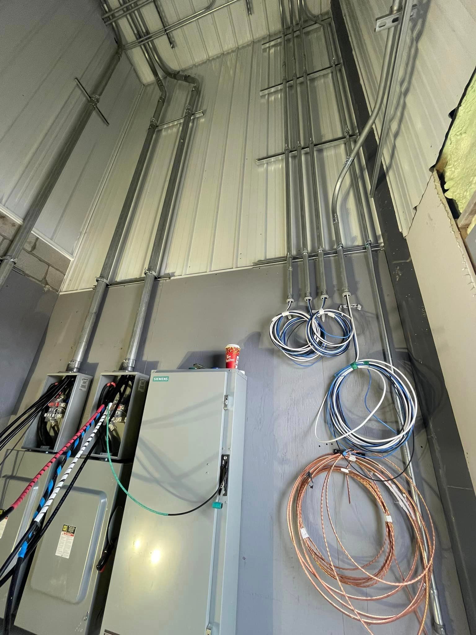Electrical conduits and panels on an industrial building interior wall.