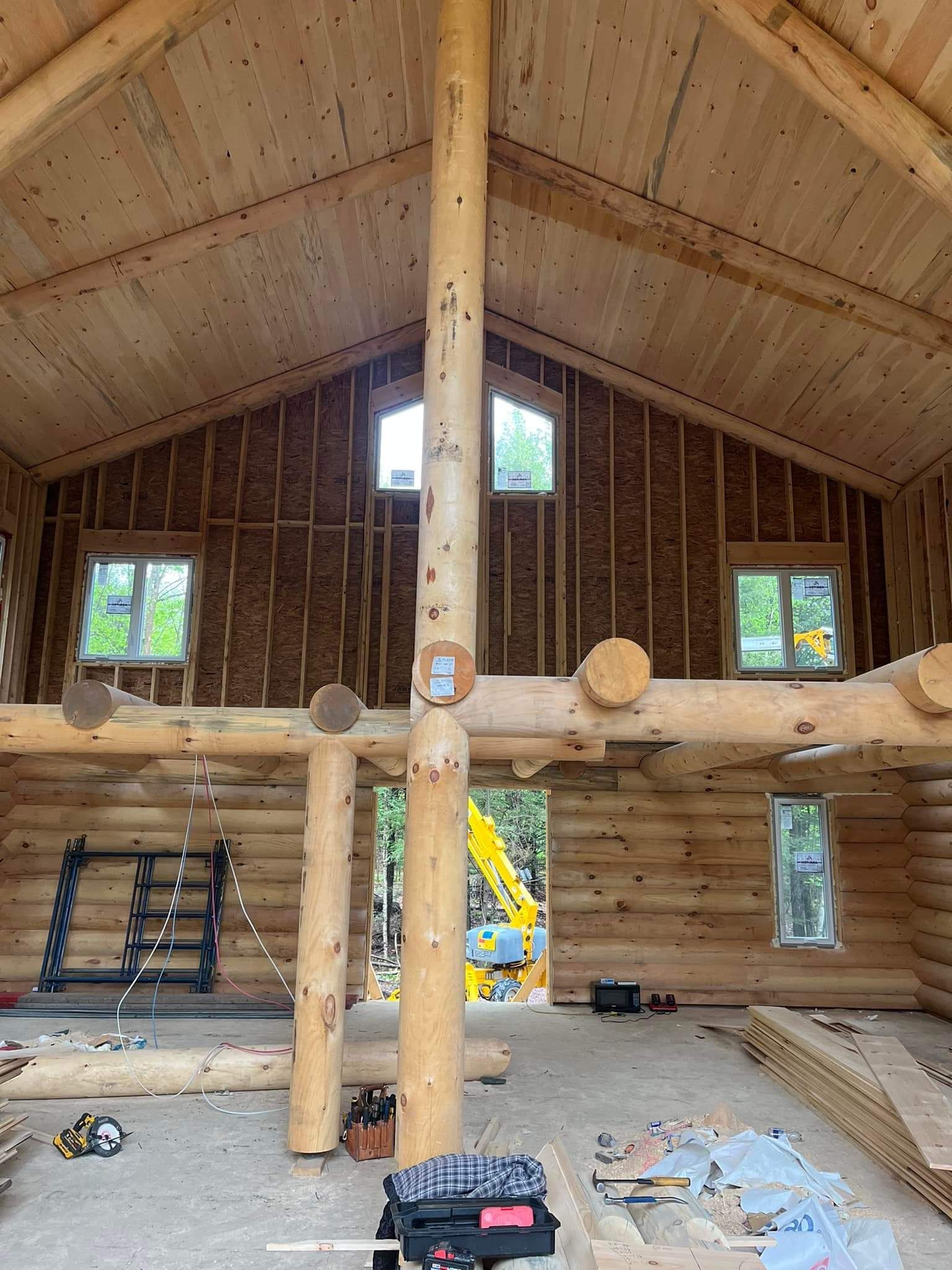 Interior of a log cabin under construction, with wooden beams and unfinished walls.