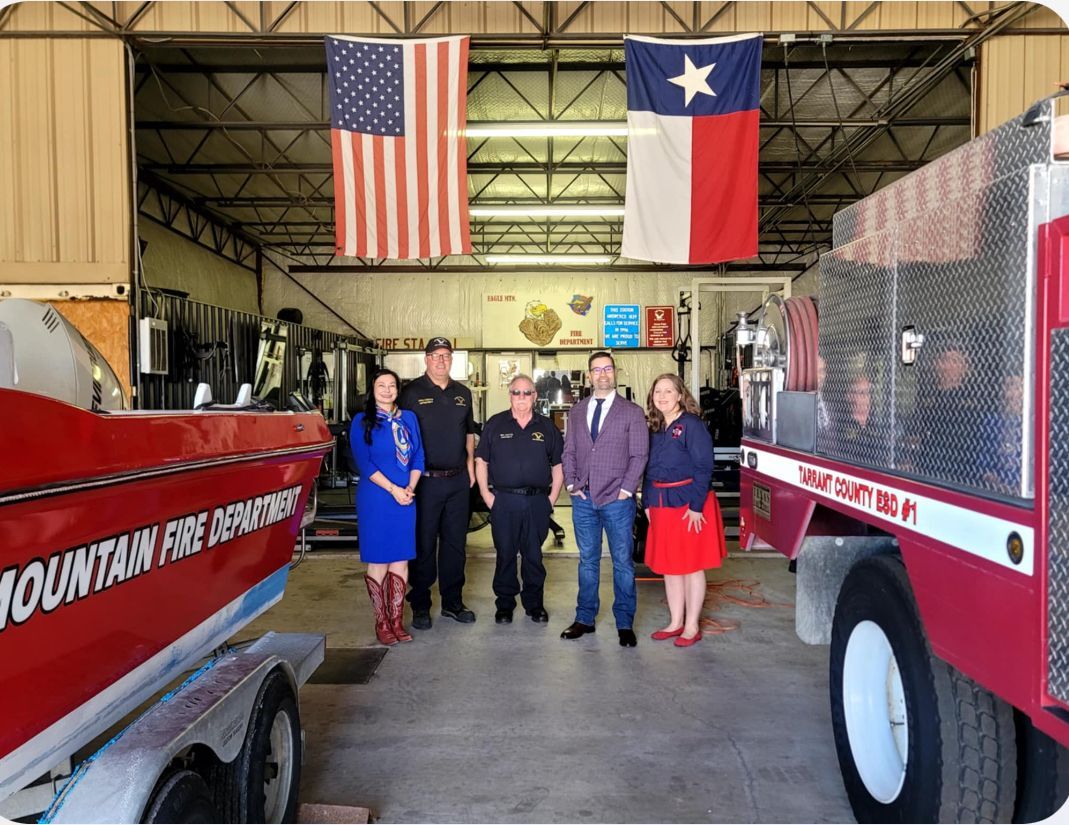 A group of people are standing in front of a fire truck in a garage.