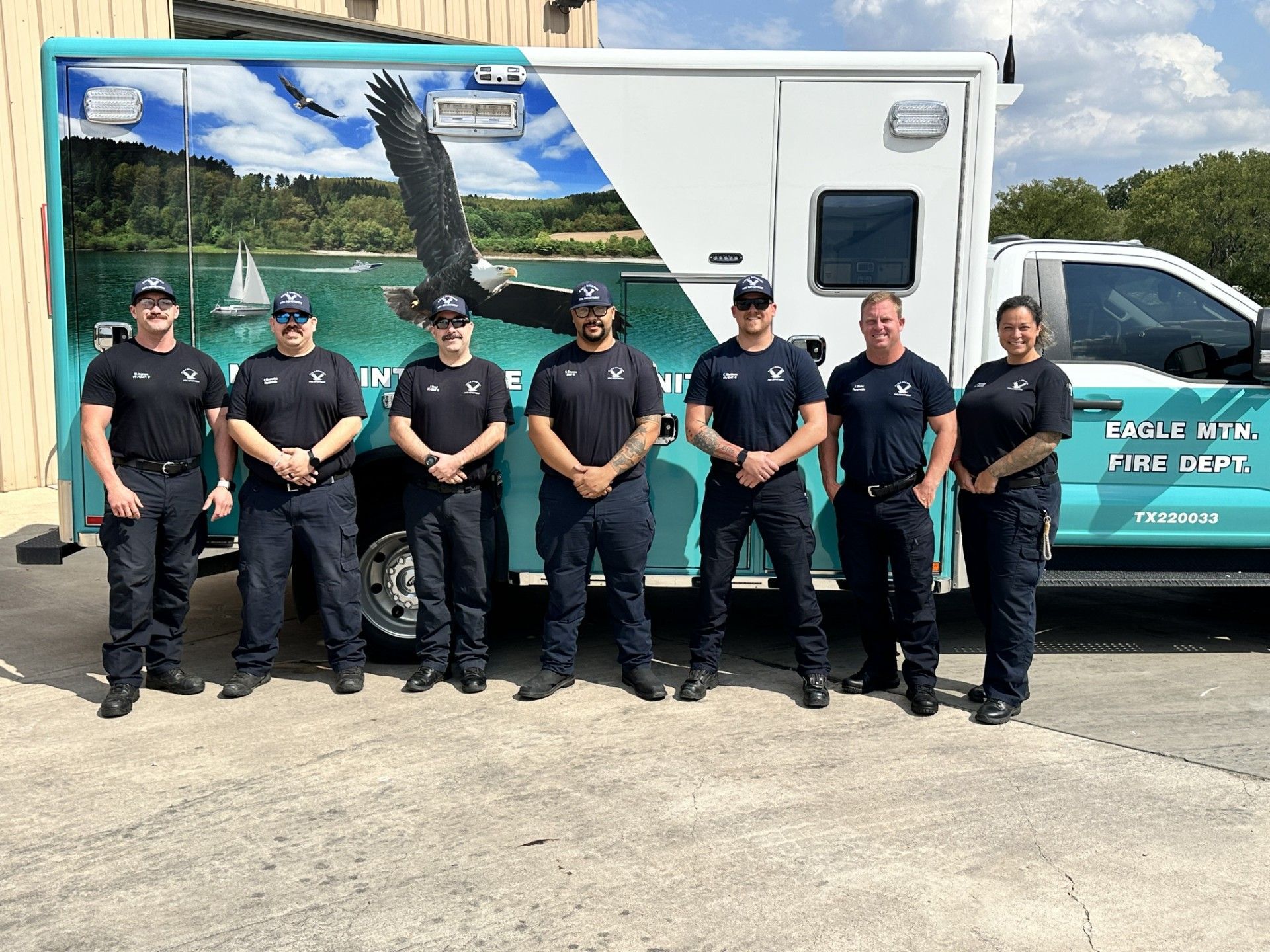 A picture of an Eagle Mountain EMS crew standing in front of the new Eagle Mountain ambulance.