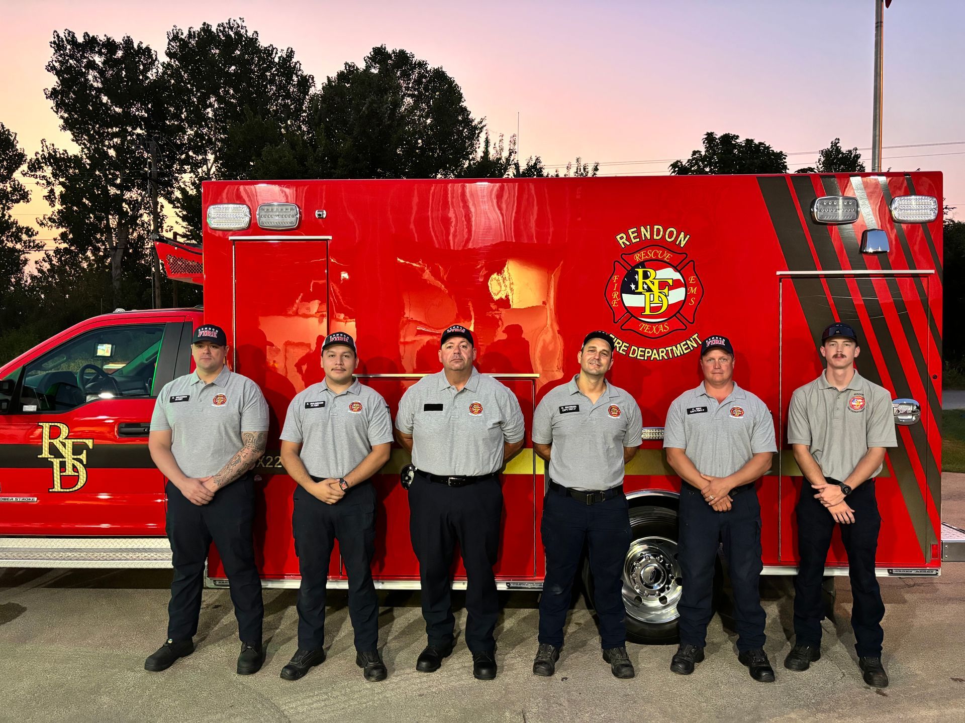 A group of EMS personnel are standing in front of an ambulance.