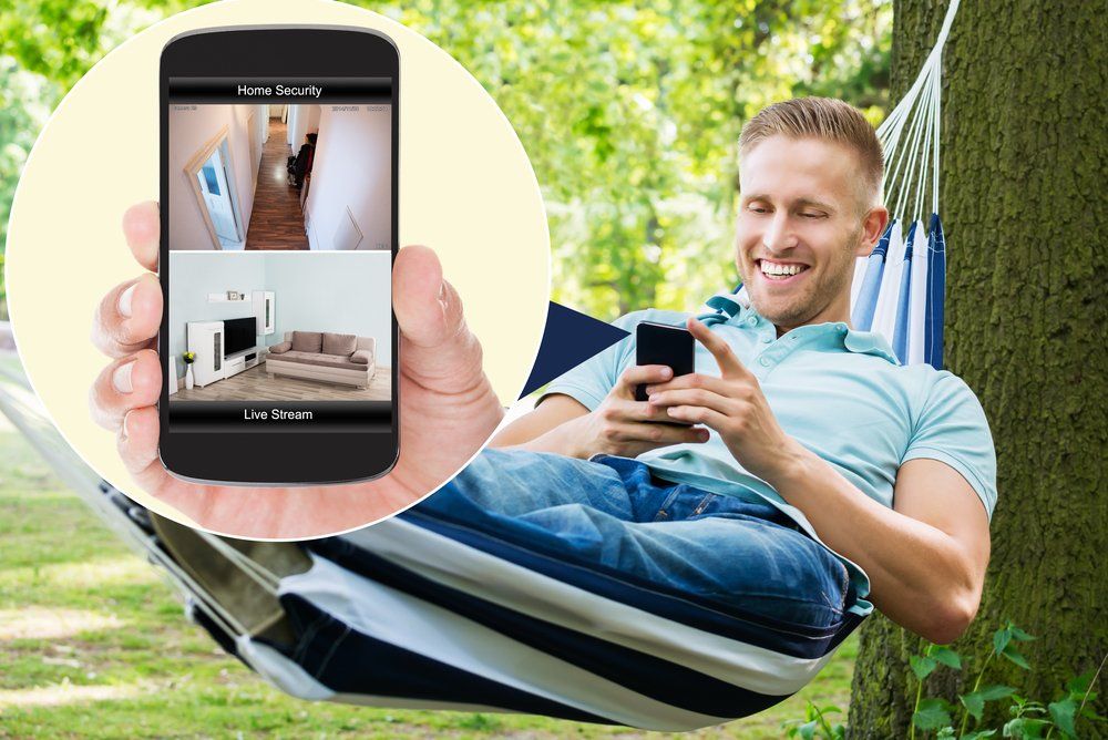 Un homme est allongé dans un hamac tout en tenant un téléphone portable.