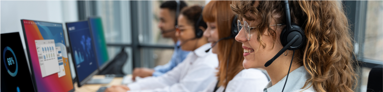 Pessoas usando fones de ouvido trabalhando em computadores de mesa em uma central de atendimento ou sala de treinamento.