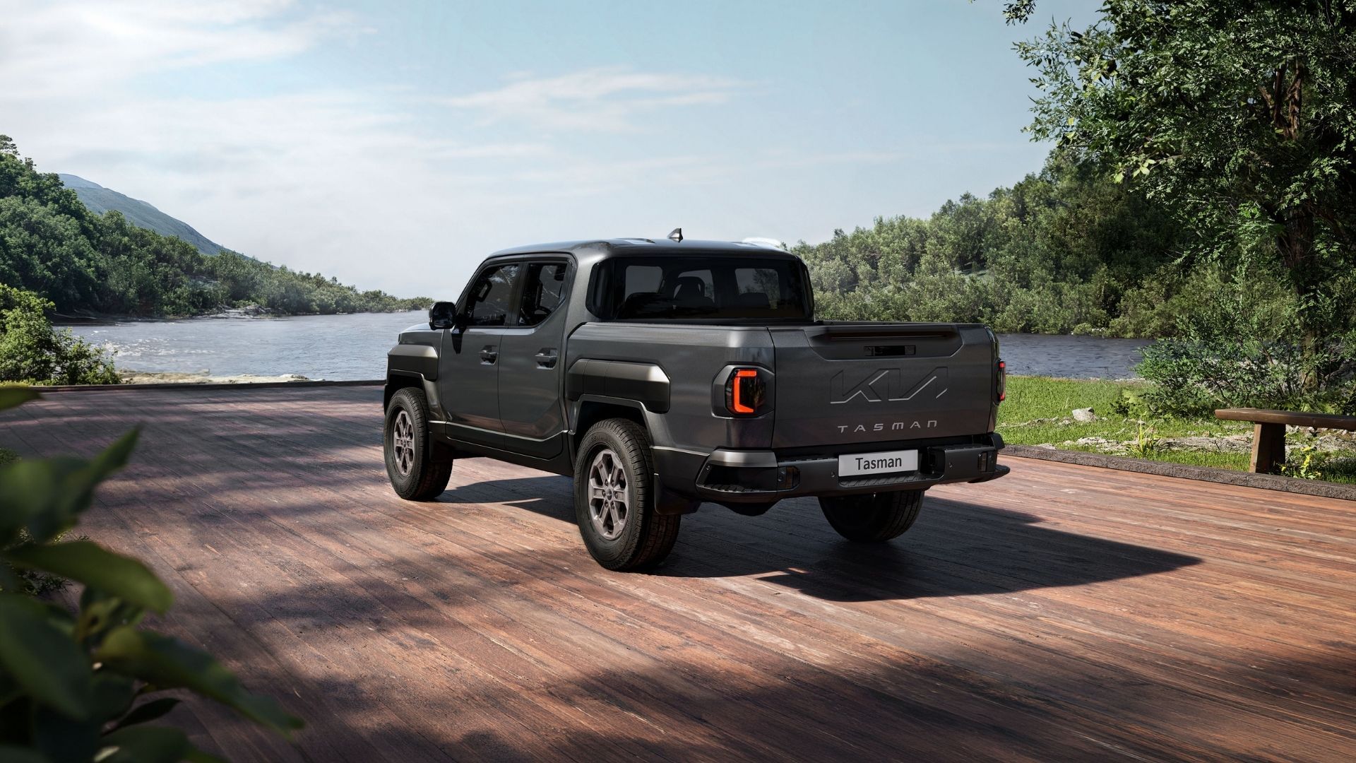 Black pickup truck parked on a brick road beside a river with green hills in the background