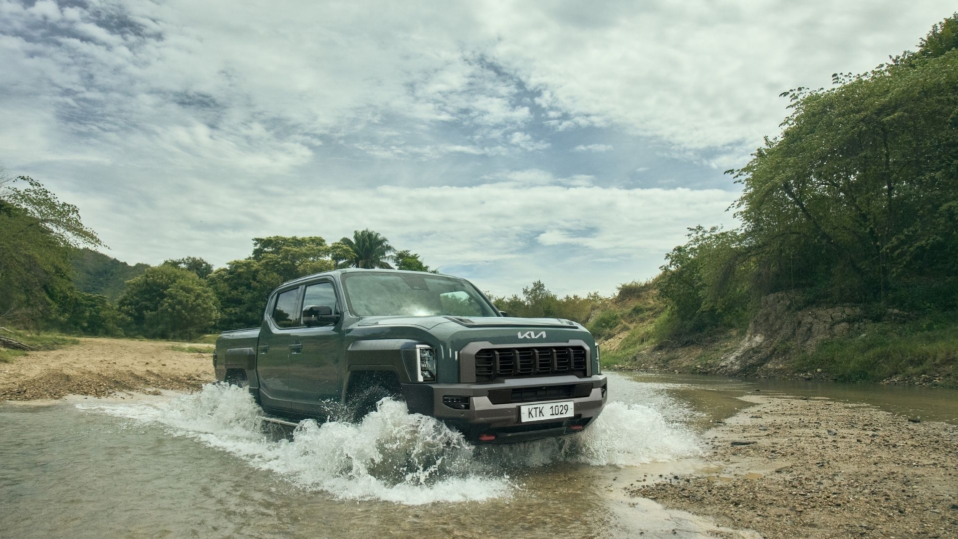 Black SUV driving through a shallow river crossing on a cloudy day.