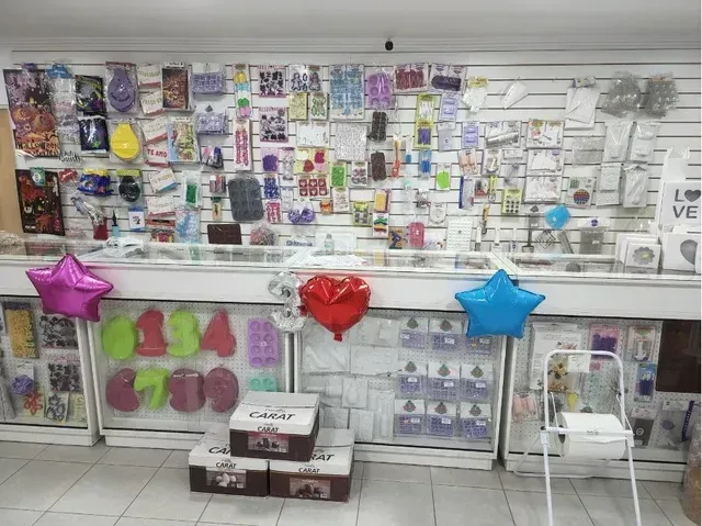 Expositor de artículos para regalos y fiestas, con globos de colores y accesorios, en una tienda