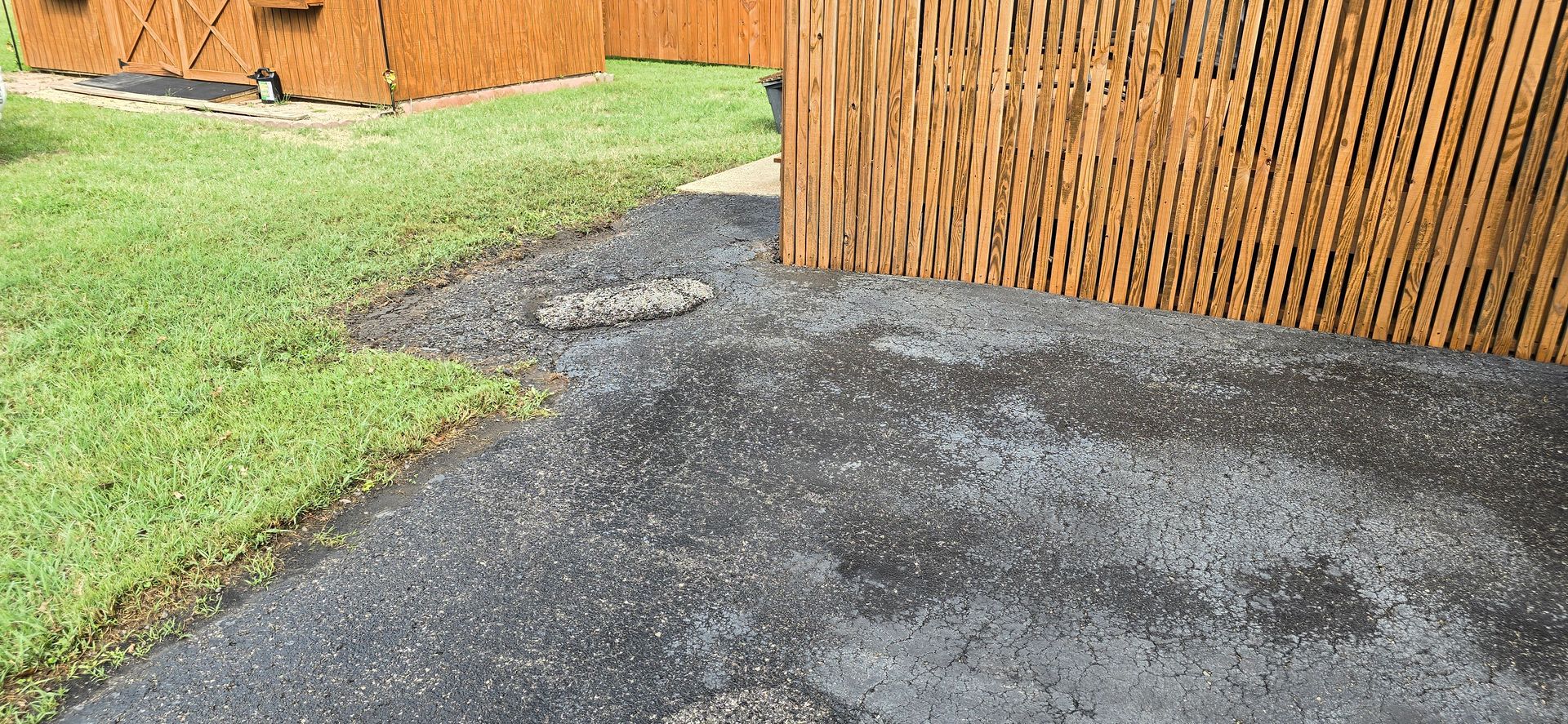 Before Asphalt Sealcoating: cracks, potholes, and oil stains on an asphalt driveway