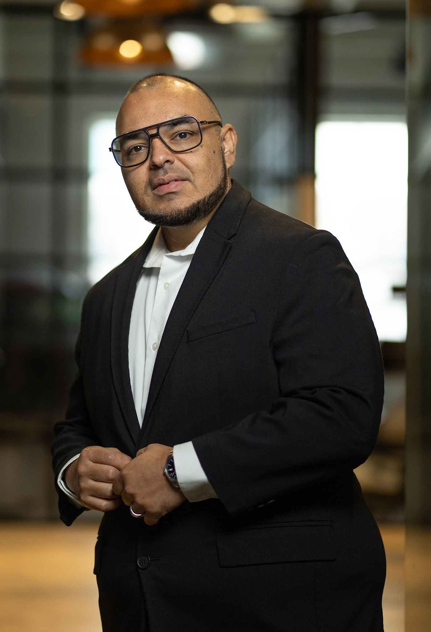 Studio portrait of a man in a black shirt and glasses against a dark background
