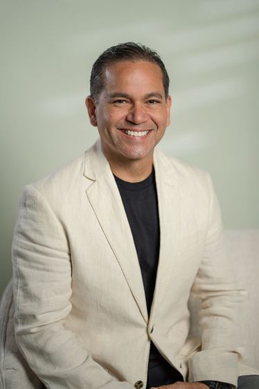 Smiling bald man in a black shirt with arms crossed on a black background