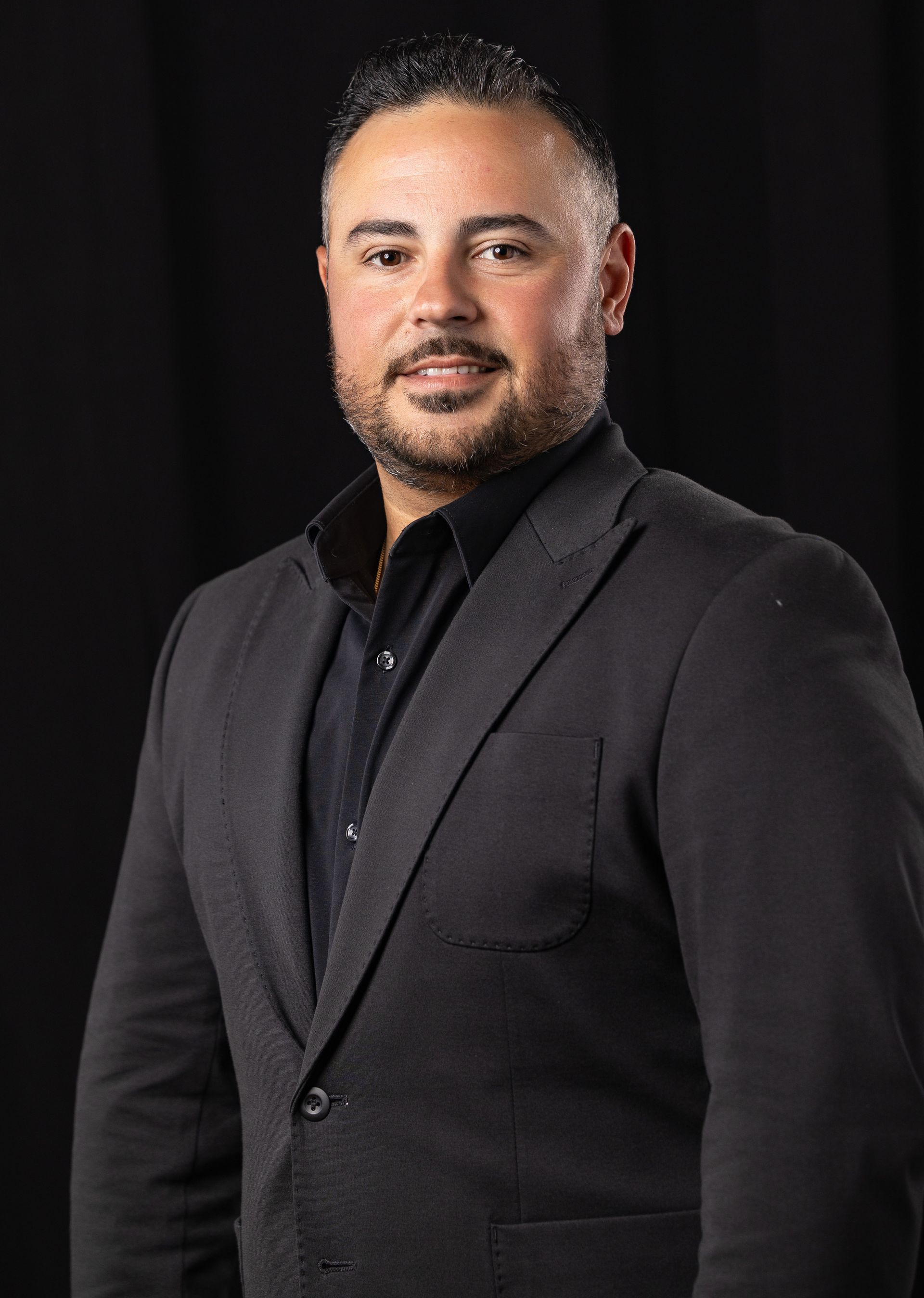 Portrait of a man in a black suit against a dark background