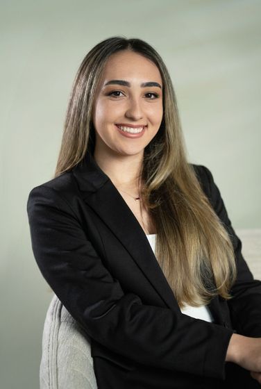 Smiling person in a black shirt against a dark background