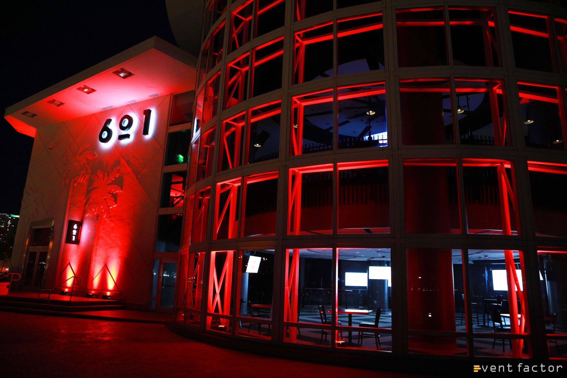 Red-lit modern building exterior at night with illuminated entrance and curved glass facade