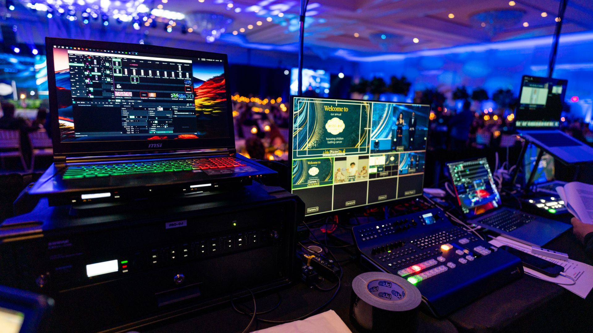 Futuristic control desk with multiple glowing monitors and keyboards in a blue-lit room