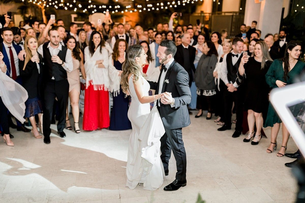 Bride and groom dancing at a wedding reception while guests cheer in the background