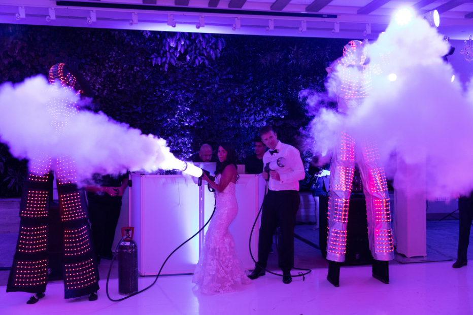 Wedding couple with smoke effects under purple lighting at an outdoor reception