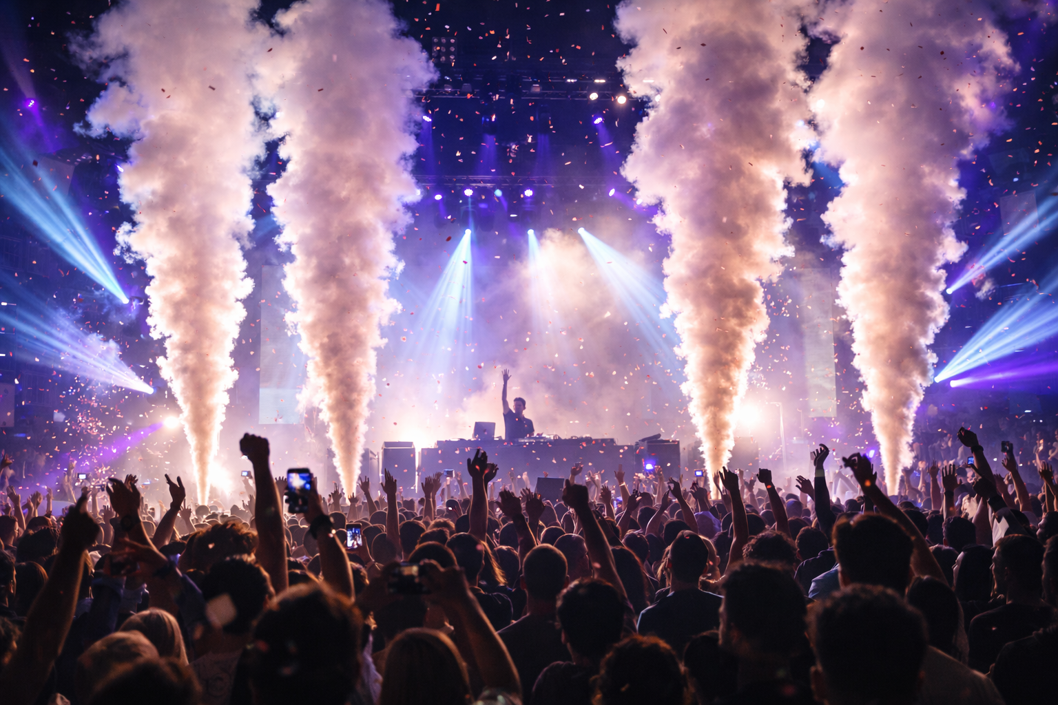 Crowd at a concert with raised hands, bright stage lights, and fireworks-like smoke plumes.
