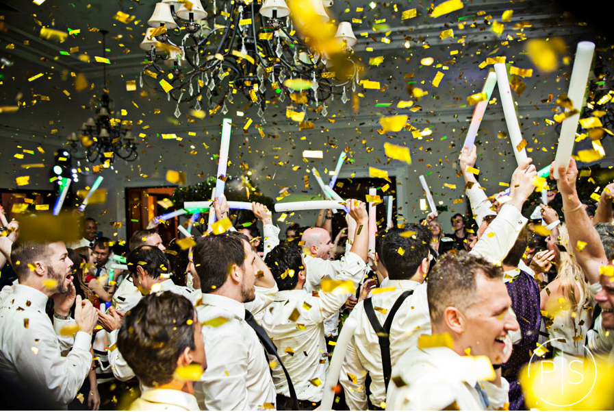 Crowd cheering amid yellow confetti and raised white thundersticks at a celebration
