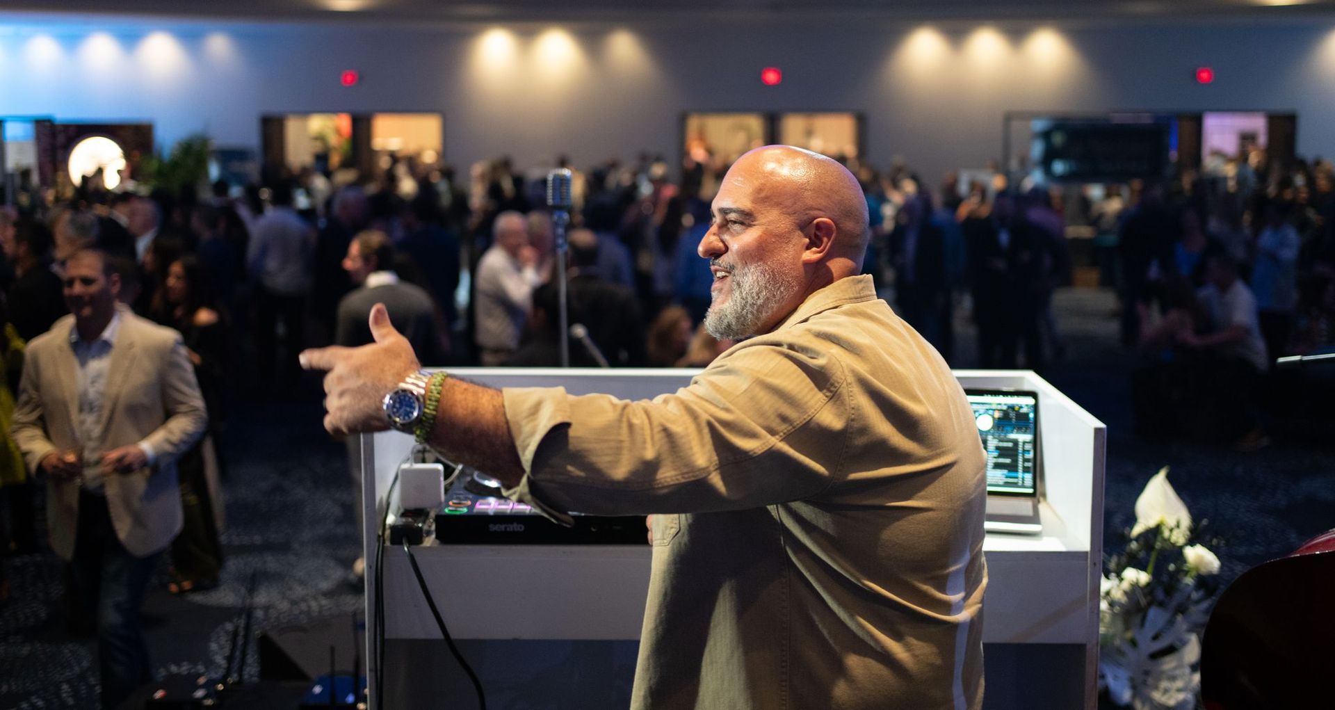 Speaker gesturing at podium to an audience in a dim conference hall