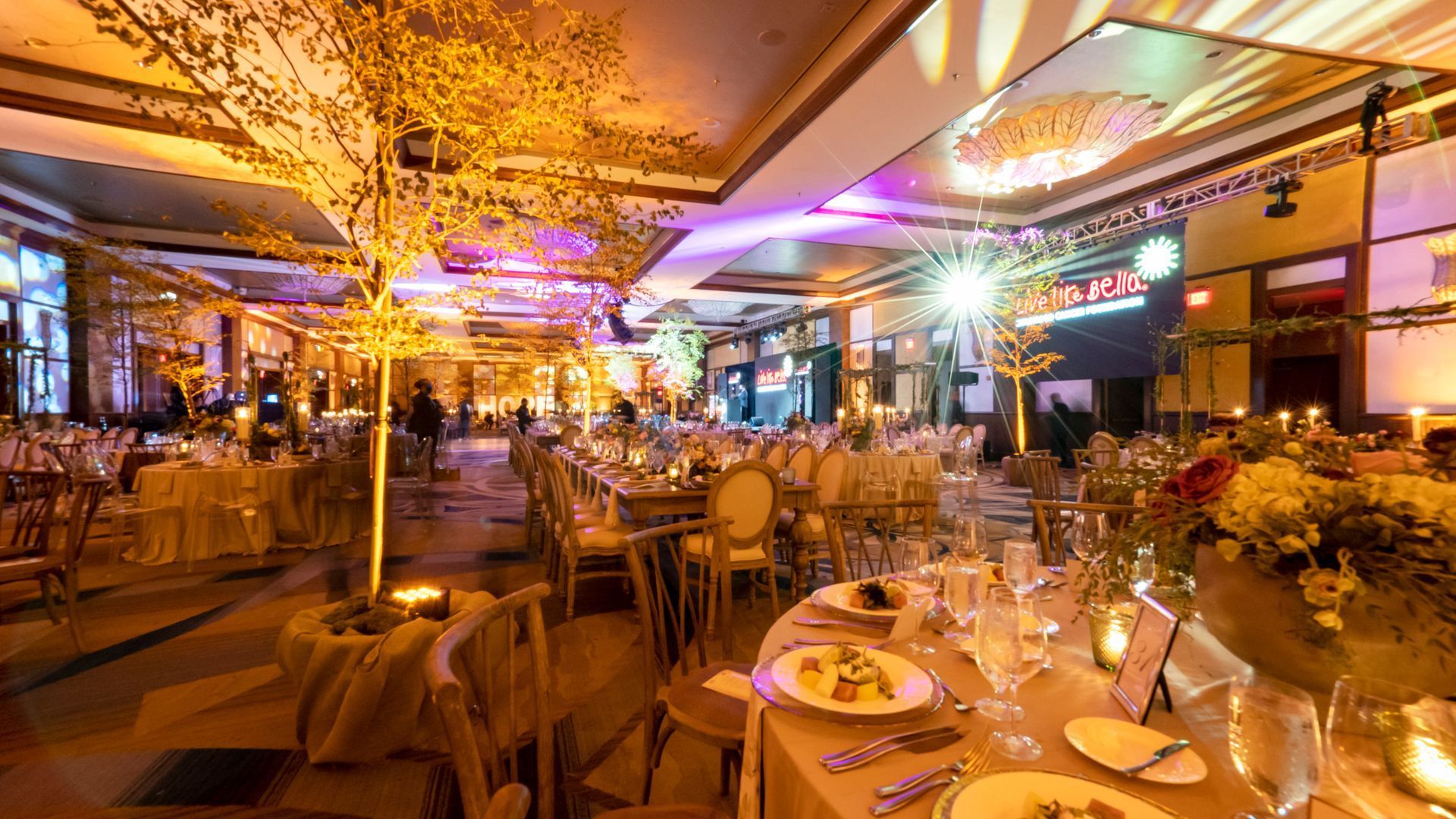 Elegant banquet hall with round tables, candles, and warm golden lighting under ornate ceilings