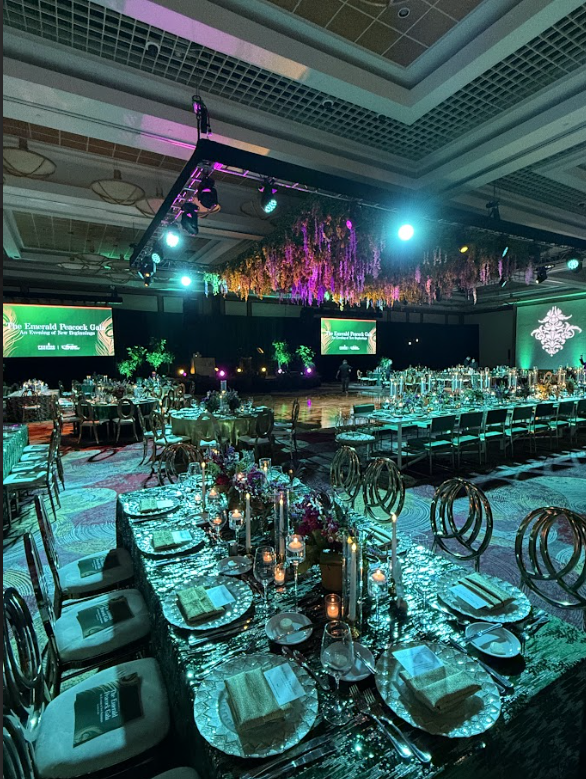 Elegant banquet hall with round tables set in teal lighting and a stage at the front
