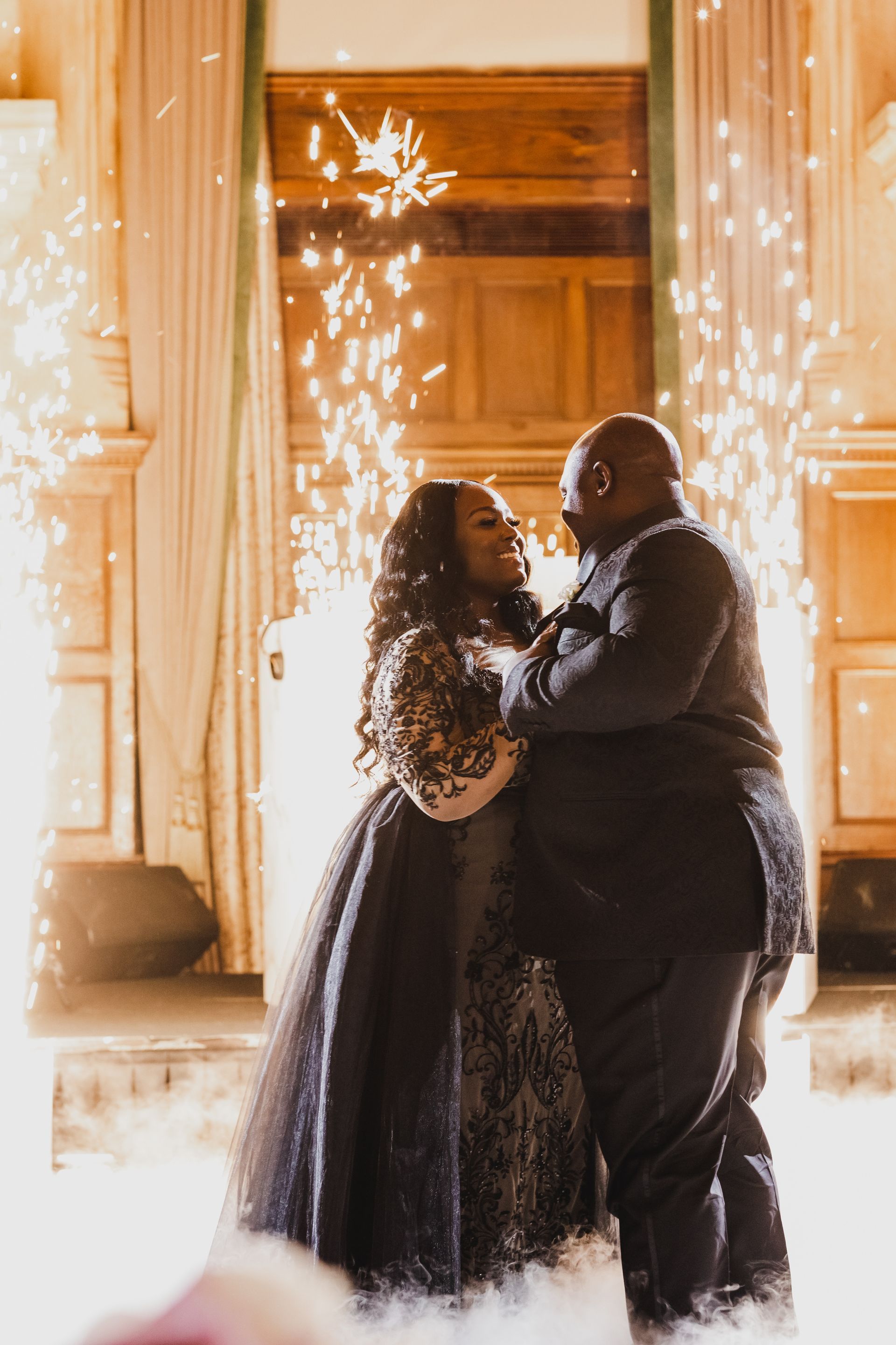 Couple dancing in a warmly lit doorway, with sparklers glowing in the background.