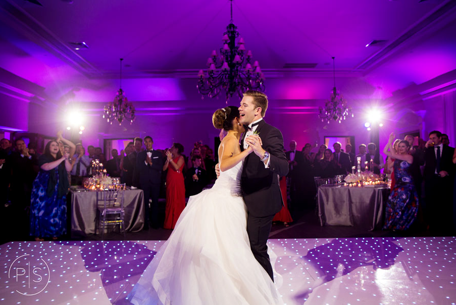 Bride and groom dancing under purple lights at a formal wedding reception