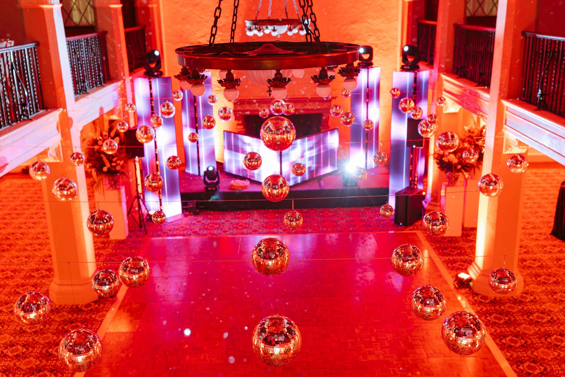 Red-lit ornate altar with candles, floral arrangements, and reflective floor in a ceremonial hall