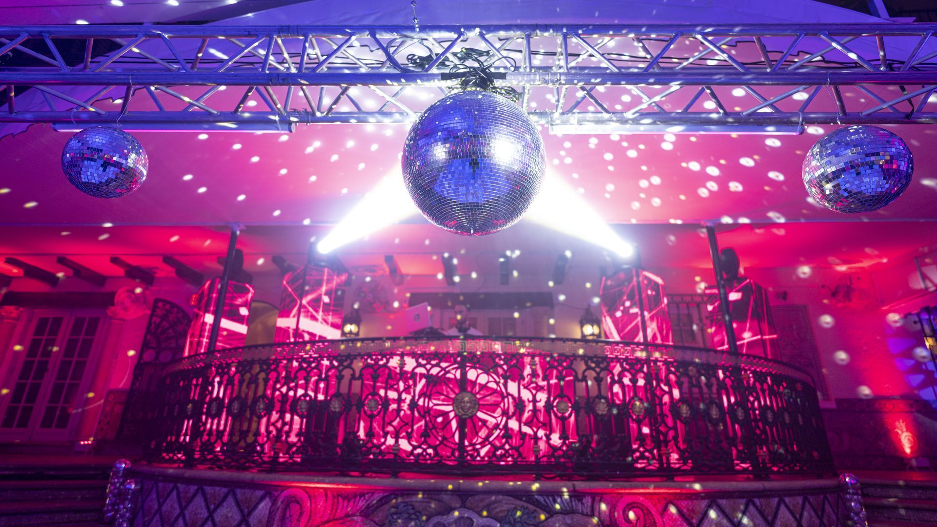 Glittering disco venue with mirrored balls, pink lighting, and a decorated balcony
