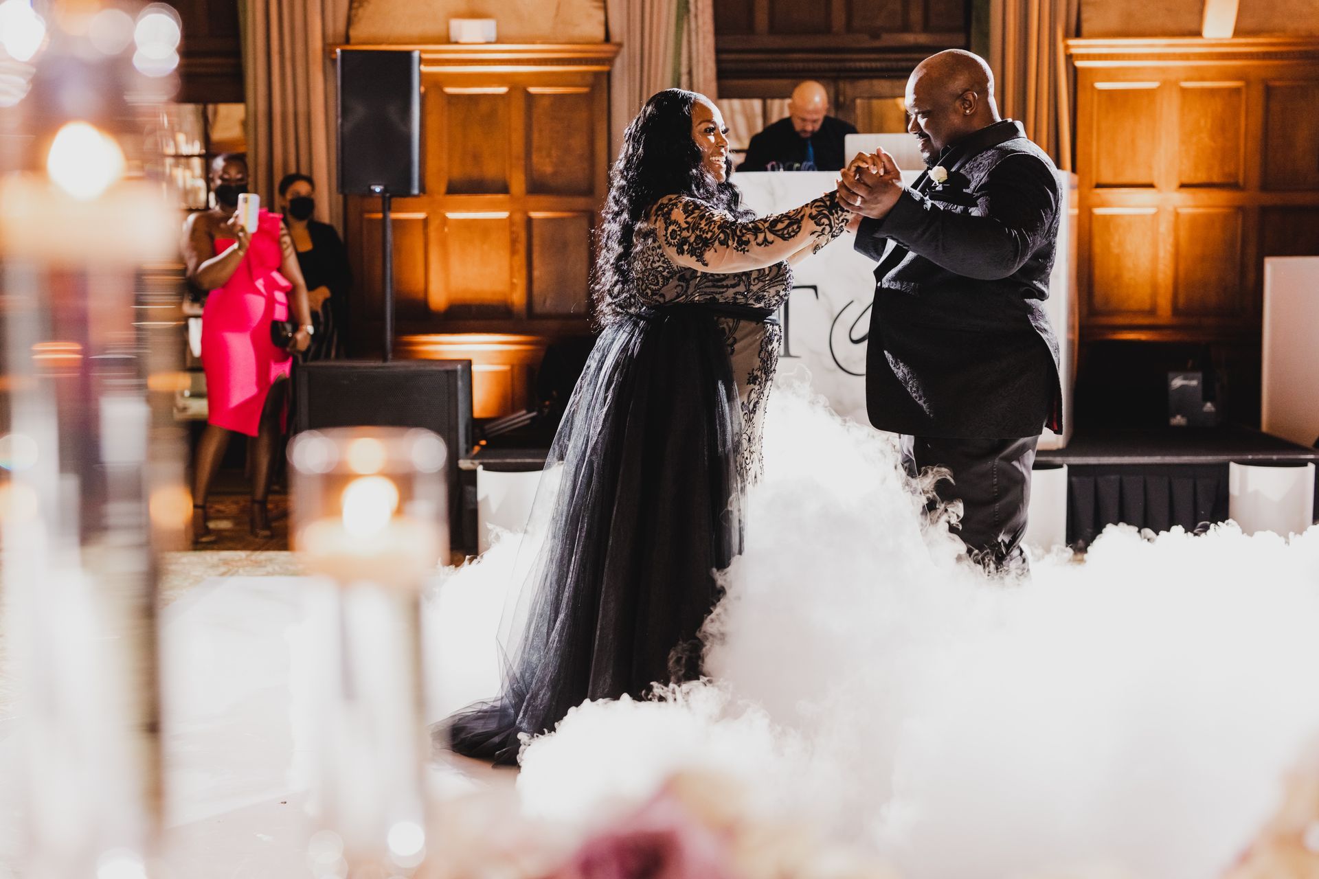 Couple dancing at a formal event with fog and warm wood-paneled backdrop