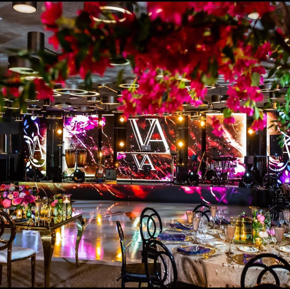 Elegant banquet hall with mirrored decor, glowing lights, and floral arrangements around set tables
