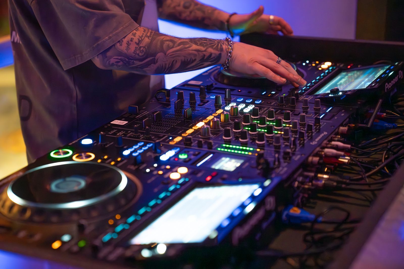 DJ mixing music on a colorful illuminated controller at a nightclub or event booth