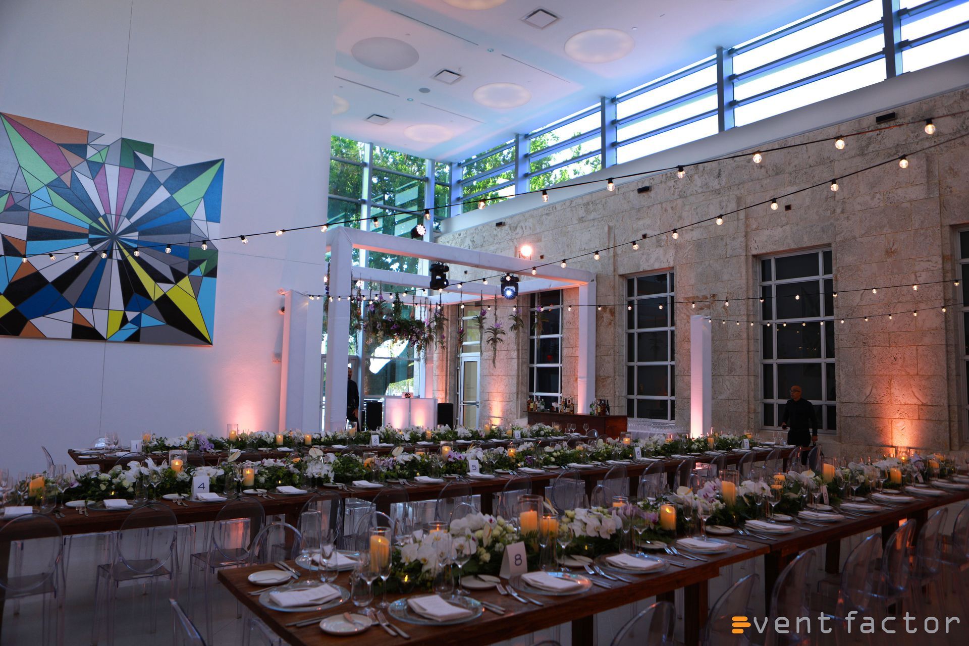 Elegant indoor banquet setup with long tables, floral centerpieces, and warm lighting in a modern venue