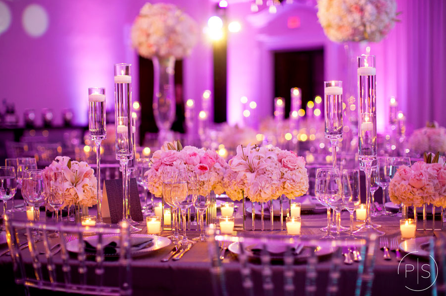 Lavish purple-lit banquet table with crystal centerpieces, candles, and pink floral arrangements