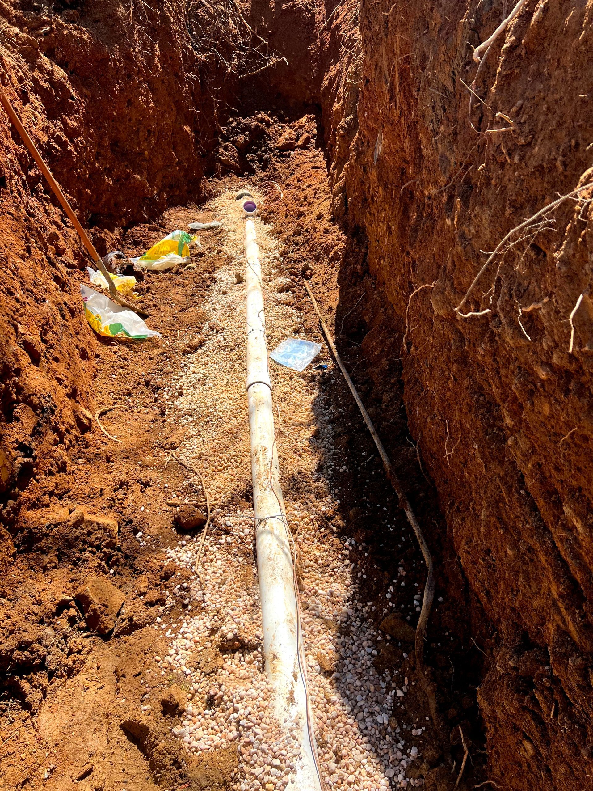 A pipe is being installed in a trench in the dirt.