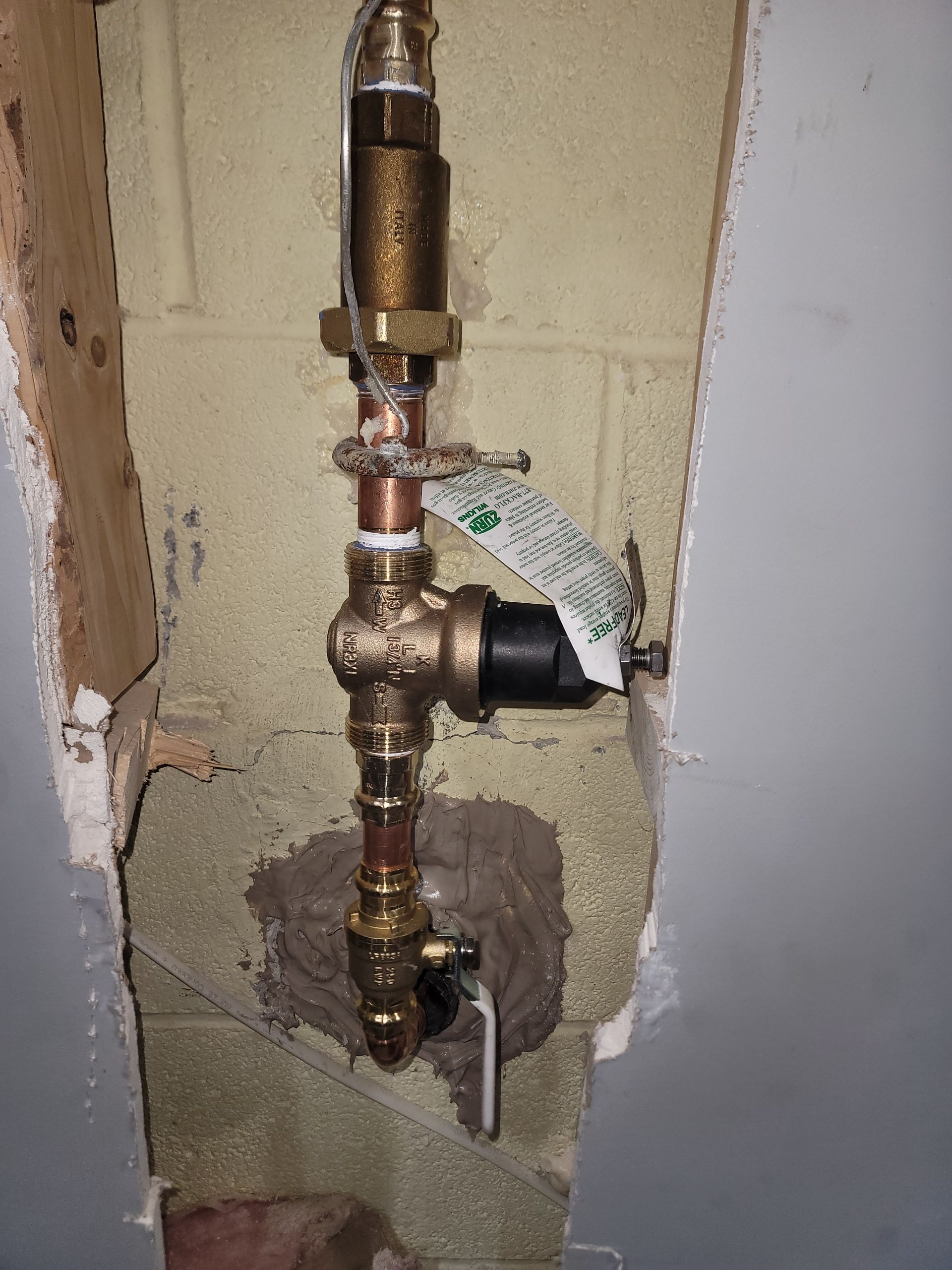A close up of a copper pipe in a wall.