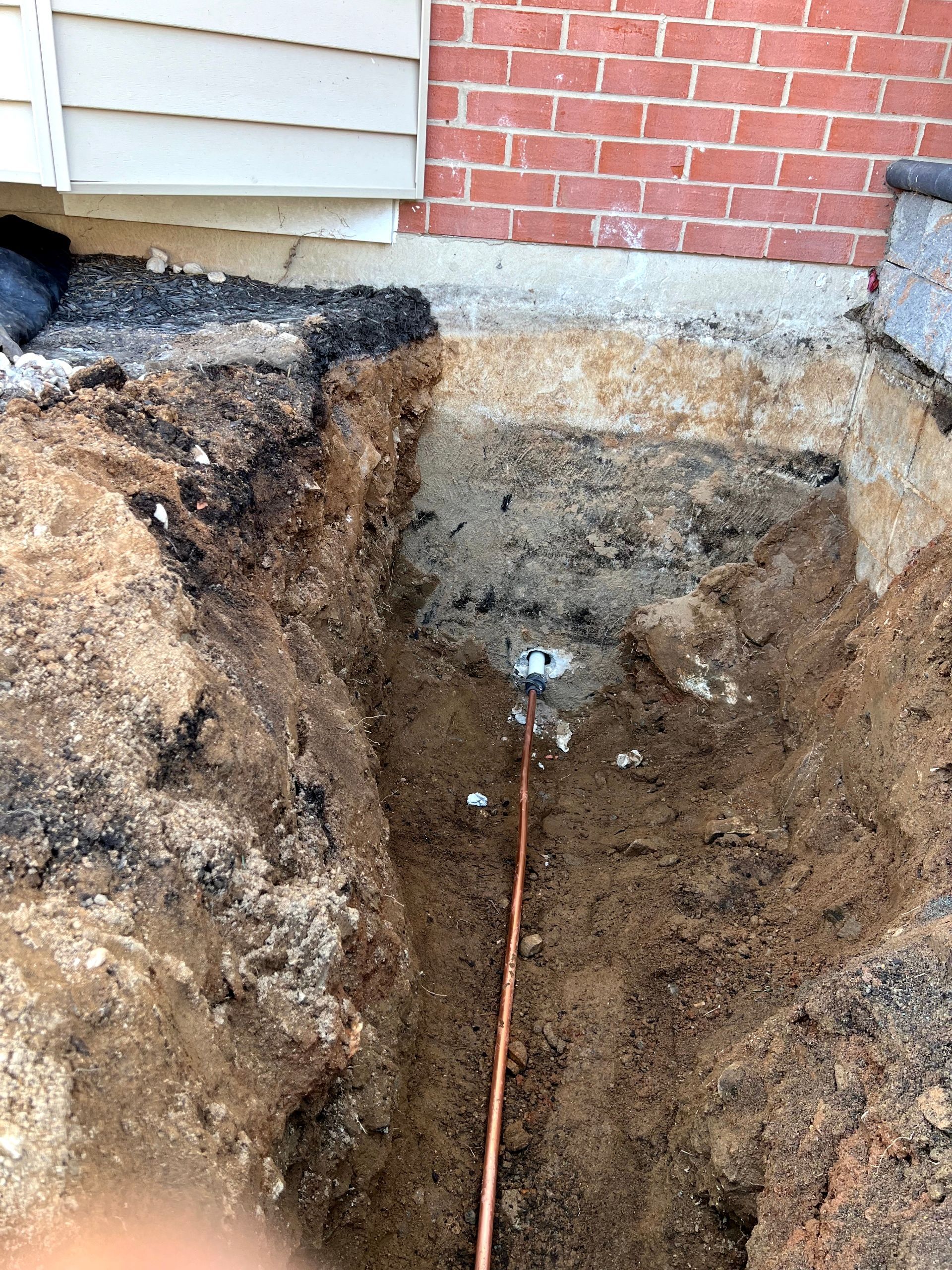A hole in the ground with a copper wire sticking out of it.