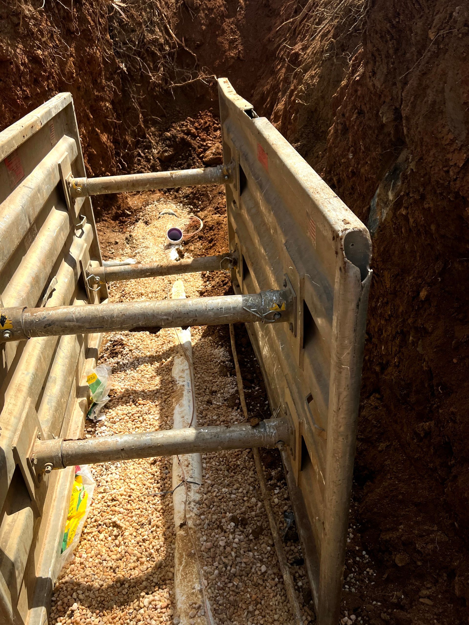 A metal barrier is sitting in the middle of a dirt trench.